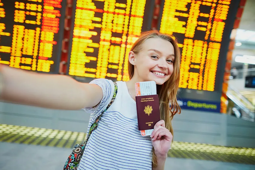 tourist girl in airport, taking funny selfie with passport