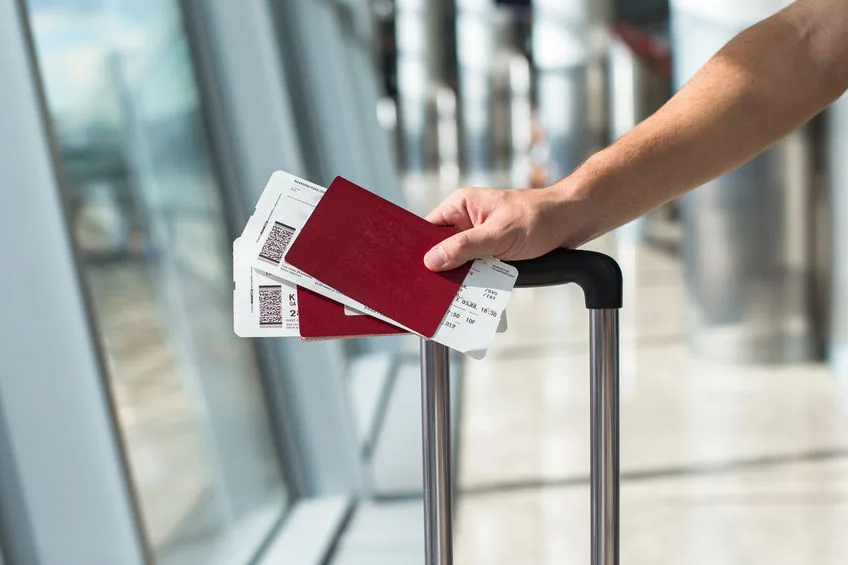 closeup of man holding passports and boarding pass at airport